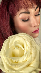 Mujer con ojos cerrados y una rosa amarilla. 
