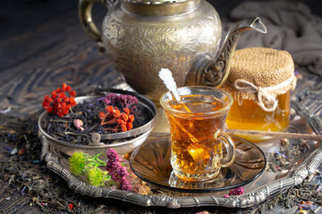 Sweet, hot tea with dry tea leaves, on an old background.