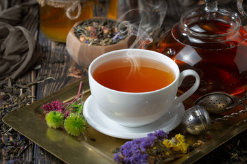 Sweet, hot tea with dry tea leaves, on an old background.