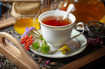 Sweet, hot tea with dry tea leaves, on an old background.