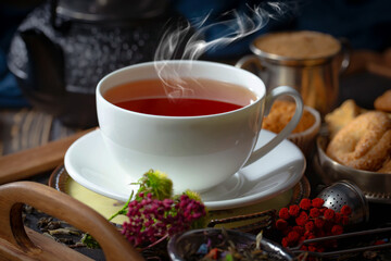 Sweet, hot tea with dry tea leaves, on an old background.