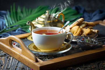 Sweet, hot tea with dry tea leaves, on an old background.