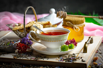 Sweet, hot tea with dry tea leaves, on an old background.