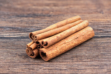 A stack of whole cinnamon sticks on a wooden background.
