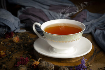 Sweet, hot tea with dry tea leaves, on an old background.