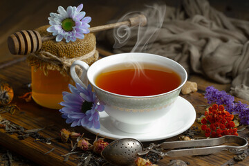 Sweet, hot tea with dry tea leaves, on an old background.