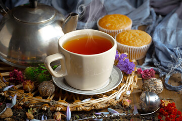 Sweet, hot tea with dry tea leaves, on an old background.