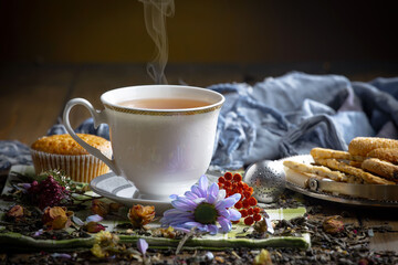 Fototapeta premium Sweet, hot tea with dry tea leaves, on an old background.