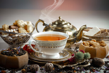 Sweet, hot tea with dry tea leaves, on an old background.