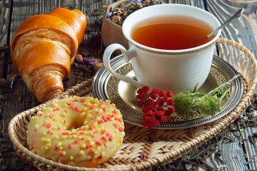 Sweet, hot tea with dry tea leaves, on an old background.