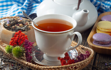 Sweet, hot tea with dry tea leaves, on an old background.