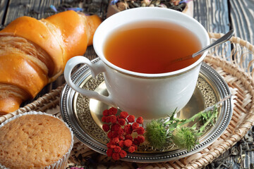Sweet, hot tea with dry tea leaves, on an old background.