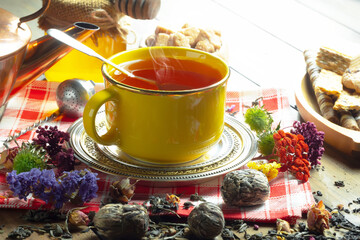 Sweet, hot tea with dry tea leaves, on an old background.