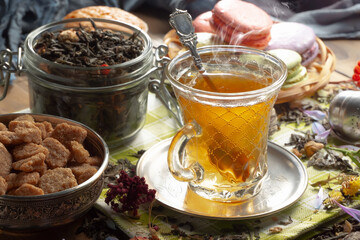 Sweet, hot tea with dry tea leaves, on an old background.