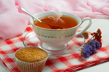 Sweet, hot tea with dry tea leaves, on an old background.