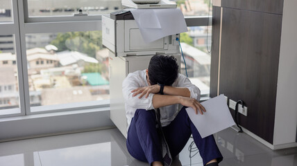 Overload office worker. Alone stressed and sad  asian office worker is sitting beside error copy machine at the office.