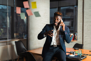 Portrait of successful businessman talking to the phone in office.