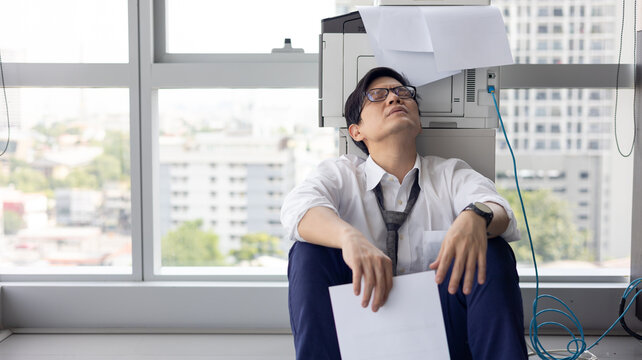 Overload office worker. Alone stressed and sad  asian office worker is sitting beside error copy machine at the office.