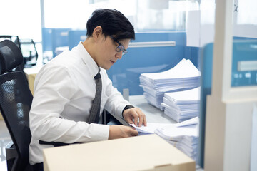 Fototapeta premium Overload office worker. Asian office worker is sitting at his desk clearing a lot of paperwork feel stressed and busy at the office.