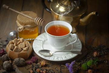 Sweet, hot tea with dry tea leaves, on an old background.