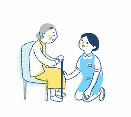 シニア女性としゃがんで話す介護スタッフ