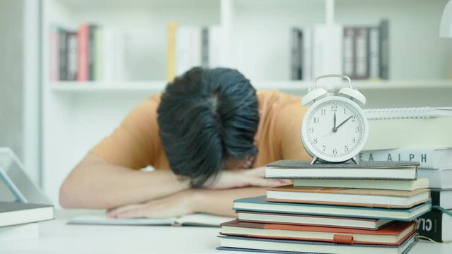 Asian student man have anxiety because of exams, male prepare for test and learning lessons in the library. stress, despair, haste, misunderstanding reading, discouraged, expectation, knowledge, tired