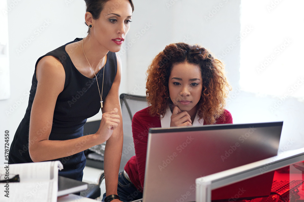 Poster collaborating on a project. two businesswoman working together at a computer in an office.