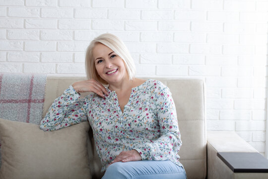 Happy woman relaxing on her couch at home in the sitting room. Age is just a number and I love every minute of it.