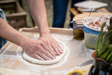 Man kneading pizza dough photo of hands preparing pizza on a wooden table outdoor - 578725591