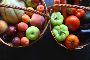 Two wickers baskets with healthy seasonal fruit nad vegetable. Dark background, top view.