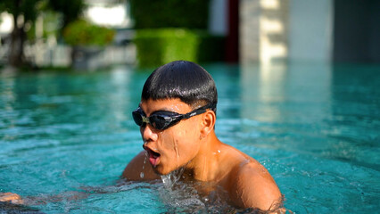  young man swimming in hotel swimming pool.