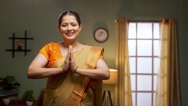 Happy smiling woman doing namaste or greeting by looking at camera - concept of welcome gesture, respect and gratitude