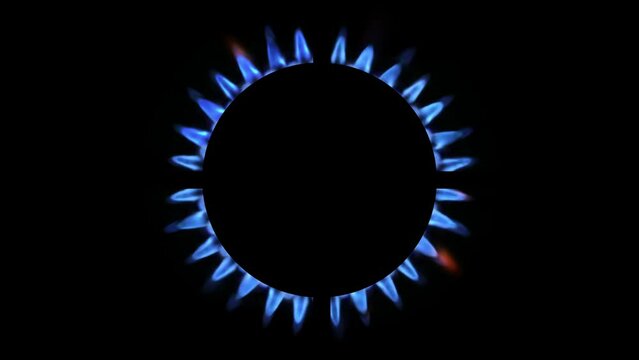 Top view of a kitchen burner glowing at night, close-up. Natural gas concept. The gas stove is switched on by a lit burner
