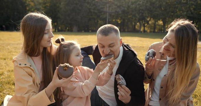 Happy Family Eating Chocolate Doughnuts On Picnic