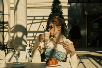 A girl in an open cafe drinking coffee from a glass