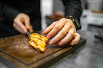 chef is cutting chicken fillet in a restaurant kitchen