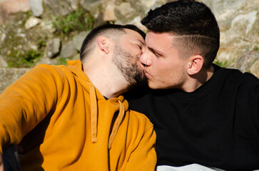 Couple of two men in love kissing in a park. Homosexuality and LGBTQ+ concept.