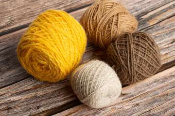 Ovillos de lana de colores sobre un fondo de madera rústico. Vista superior y de cerca - obrazy, fototapety, plakaty