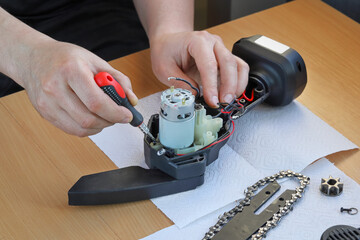 Repair, Hands fix new electric engine in chain saw body