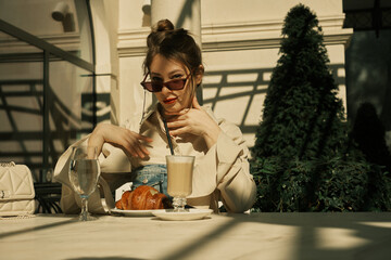 A girl sits at a table in a cafe and looks through a camera lens
