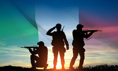 Fototapeta na wymiar Silhouettes of a soldiers with Italian flag against the sunset. Armed Forces of Italy. EPS10 vector