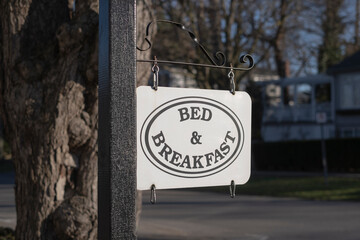 Bed and breakfast sign in tourist town. Selective focus, blurred background, sunny day. Small...
