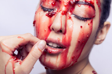 Woman with open mouth and closed eyes touching fingers her lips and tries, jam flowing on her face.
