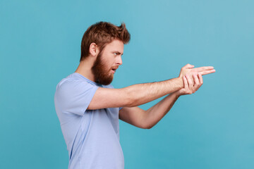 Side view of focused bearded man pointing finger gun gesture to target, threatening to kill.