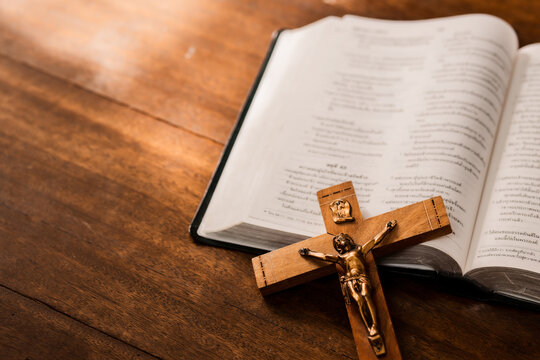 Close up of Jesus's crucifix over bible on wooden table background, copy space