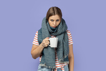 Woman in warm scarf, posing with sad upset expressing drinking cup of tea.