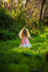 Little girl in a dress playing at the woods.