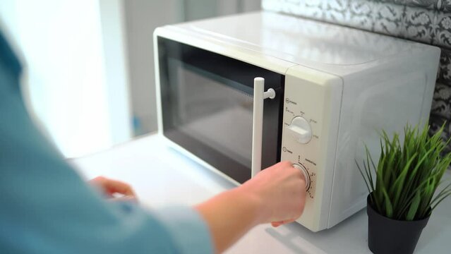 Woman warming up food in the microwave oven