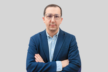 Portrait of a confident business man with crossed arms looking at the camera on a gray background.