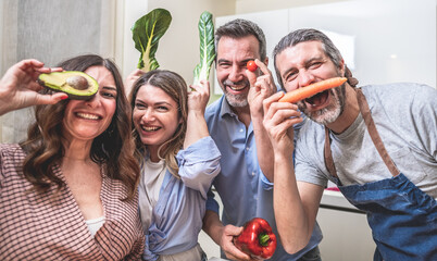 Four adult friends cooking together and taking photos  with bio food in the kitchen